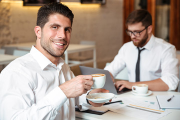 Portrait of a smiling handsome businessman drinking coffee