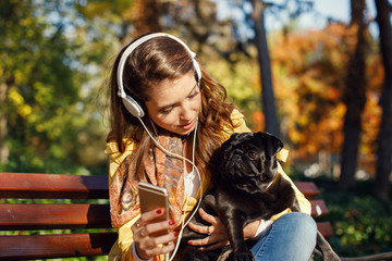 Young woman enjoys music with her dog in the park