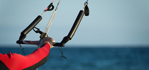 Kitesurfer ready for kitesurfing rides in blue sea detail control bar