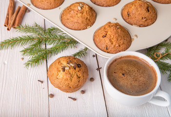 Christmas cupcakes with spices cloves, seeds and nuts and cup of coffee in a baking dish on white wooden table. Christmas celebration at home concept