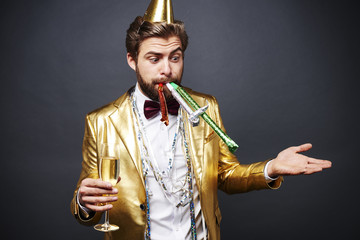 Astonished man with party blower standing with champagne flute