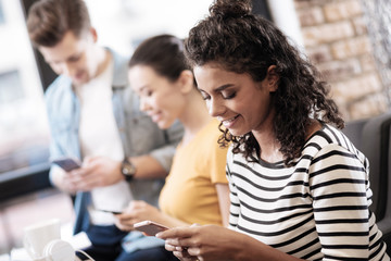 Curly-haired girl sitting and using her phone