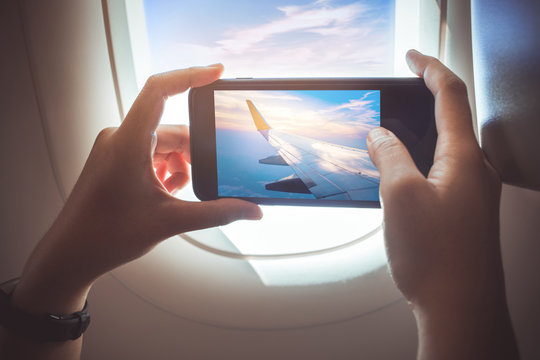 Female taking a photo with smartphone on plane.Holiday travel and journey concepts