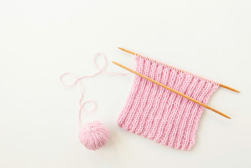 Pink scarf and thread ball, wooden knitting needles