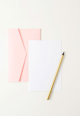 Pink envelope, blank paper, golden pencil on white background