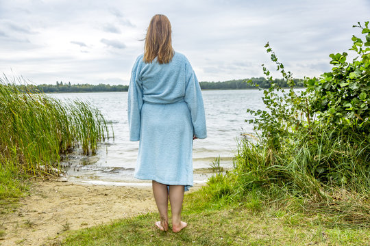 Young woman with bathrobe at the lake