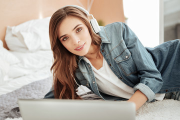 Smart young lady in headphones working on laptop