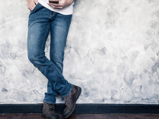 Close up of Man's legs in jeans and boots on wooden floor. Free space for text