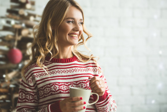 Young beautiful woman drinking cup of coffee blurred winter snow tree background.
