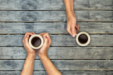 Coffee mugs hands holding on wood table, top view angle - 178662603