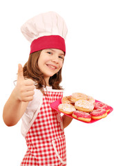 happy little girl cook with sweet donuts and thumb up