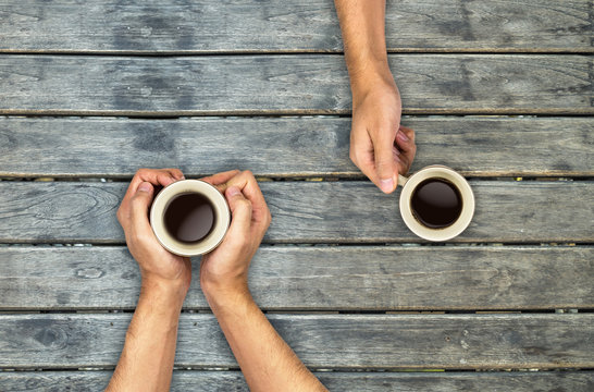 Coffee Mugs Hands Holding On Wood Table, Top View Angle