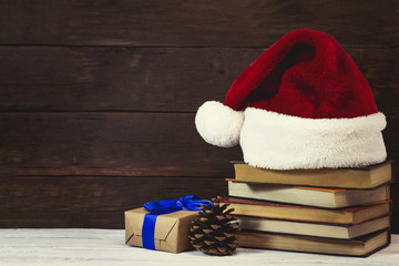 Obraz na płótnie Canvas Santa Claus hat, packing box wrapped in craft paper, cone, books