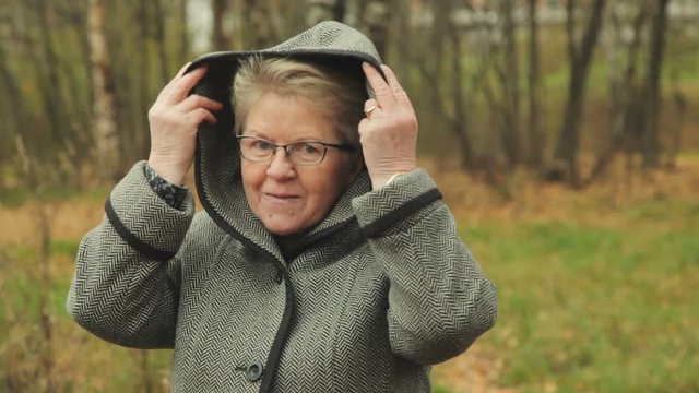 Granny with black glasses, wears a hood on his head. her hair gray.