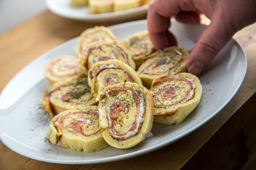 Mann nimmt Lachsrolle aus Omelette und Frischkäse mit Dill