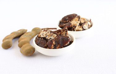 Tamarind fruit in a bowl and tamarind pods.