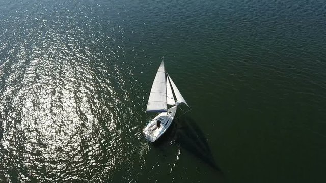 An astonishing bird`s eye shot of a white yacht floating in the Dnipro river on a sunny day in summer. It looks dreamlike and beautiful. The riverscape is fine and nice with its dark blue waters.