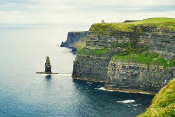 Fototapeta na wymiar Cliffs of Moher, west coast of Ireland, County Clare on wild Atlantic ocean. Photo of a beautiful scenic sea and sky landscape. View of ocean scenery. Lightly toned, horizontal