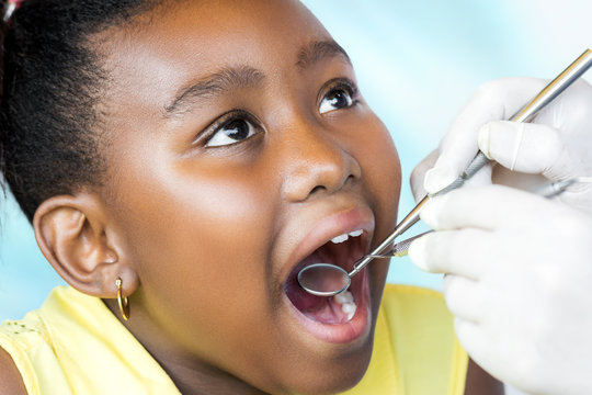 Little black girl having dental checkup.