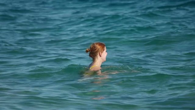 Girl swims in the sea, slow motion