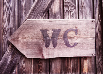 An old, wooden restroom sign with arrow
