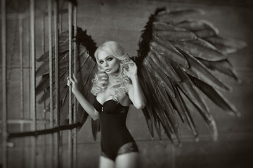 blond woman with black wings in a cage. Angel, mysticism