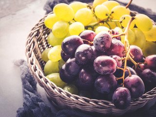 White and dark grapes in a basket on gray. Abstract minimal fruit still life