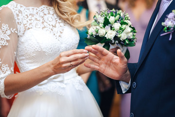 The hands of the newlyweds. A womens's hand puts on a ring. Bride hands close-up.