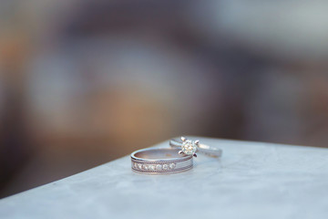 Engagement and wedding rings over each other. For Love story . Marble on the stone.