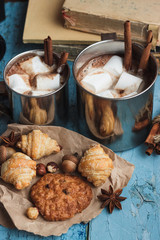 Metal cups with cacao and marshmallow and different cookies
