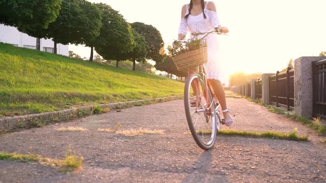 Young beautiful woman standing near her bicycle at sunset. Slow motion