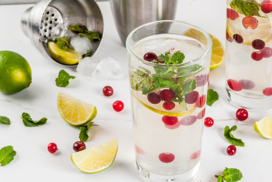 Fall and winter refreshment drink, cranberry mojito cocktail with lime and mint, on white table, copy space