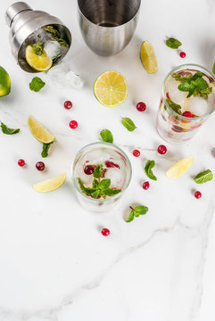 Fall and winter refreshment drink, cranberry mojito cocktail with lime and mint, on white table, copy space