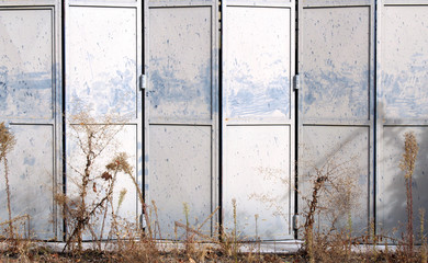 Old and damaged metal gray folding door on an abandoned warehouse