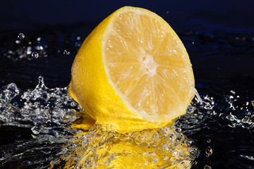Lemon Slices falling deeply under water with a big splash on blue background