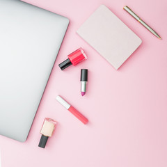 Home feminine desk with laptop, notebook and cosmetics on pink background. Top view. Flat lay lifestyle concept.