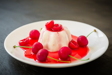 Fruit dessert with cherry on black wooden table.