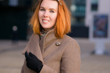 Business girl smiling. bright, red hair. against the backdrop of a business city with glass. he's going to work businesswoman