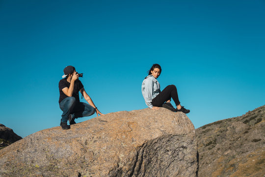 Man taking pictures of woman on rock