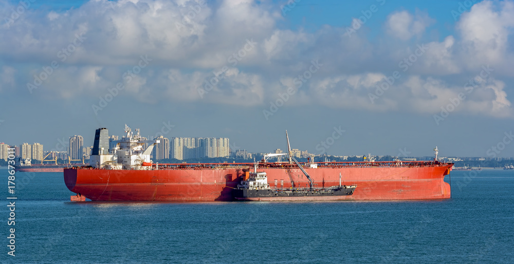 Wall mural Loading anchored oil supertanker via a ship-to-ship oil transfer (STS) from raid tanker