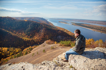Naklejka na ściany i meble a man sits on top of a mountain admiring the scenery