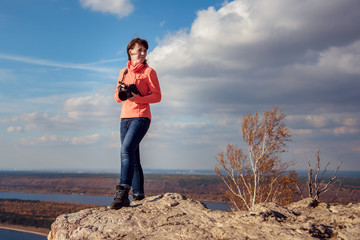 Naklejka na ściany i meble the girl stands on top of the mountain and takes pictures of the landscape