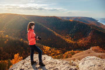 the girl stands on top of the mountain and takes pictures of the landscape