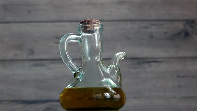glass bottle filled with olive oil spinning on wooden background