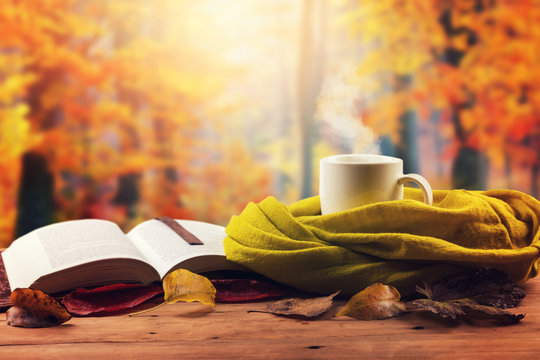 autumn mood - opened book, scarf and hot drink on the table