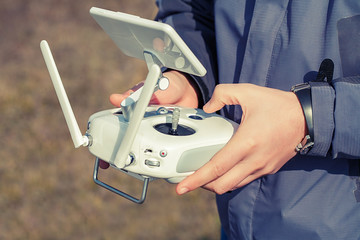 Man holds a drone remote controller in his hands. Close-up of quadrocopter RC during flight. Pilot...