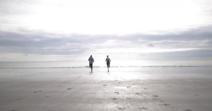 Senior couple jogging to coastline