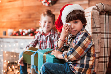 Beautiful happy laughing children brothers  play with gifts in hand in a Christmas interior with a Christmas tree. The concept of a family holiday