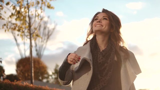 charming young woman walks through the autumn city in a coat and smiles.