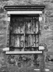 old black shuttered window set in a cracked wall